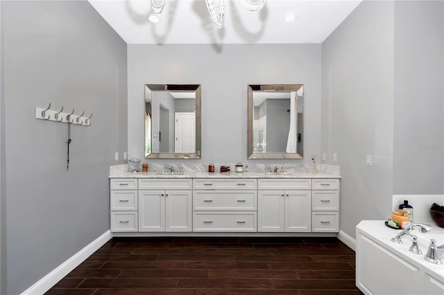 full bathroom featuring baseboards, double vanity, a sink, and wood finish floors