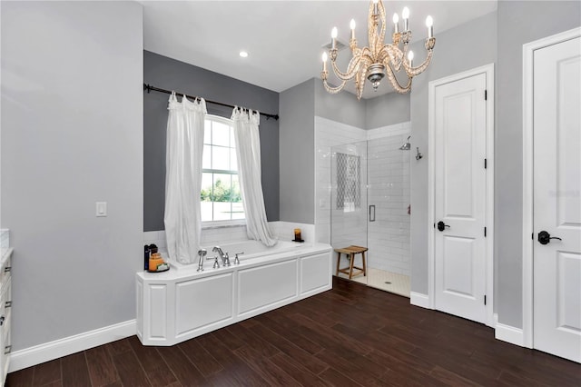 bathroom with a garden tub, wood finished floors, a stall shower, and a notable chandelier