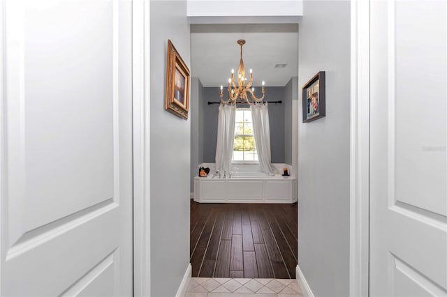 corridor with a notable chandelier and dark wood-type flooring