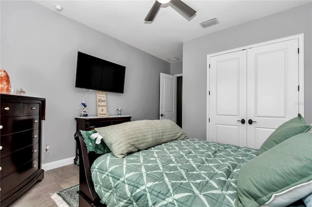 bedroom featuring a closet, visible vents, baseboards, ceiling fan, and tile patterned flooring