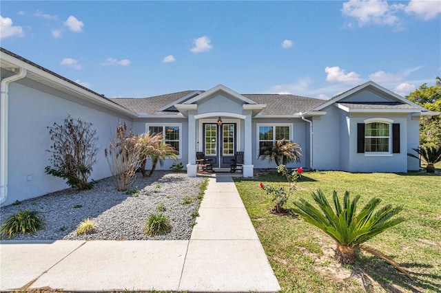 ranch-style house with french doors, a front yard, stucco siding, and roof with shingles