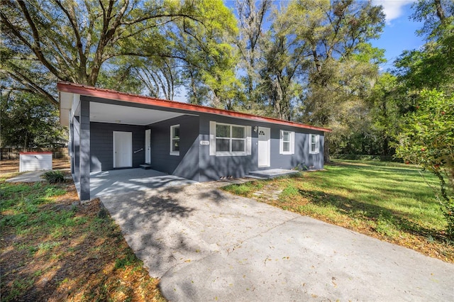 view of front facade with an attached carport, concrete driveway, and a front lawn