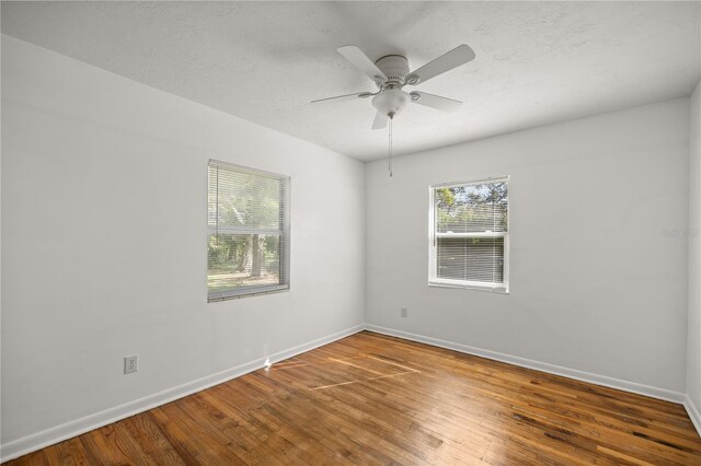 empty room with ceiling fan, baseboards, a textured ceiling, and hardwood / wood-style floors