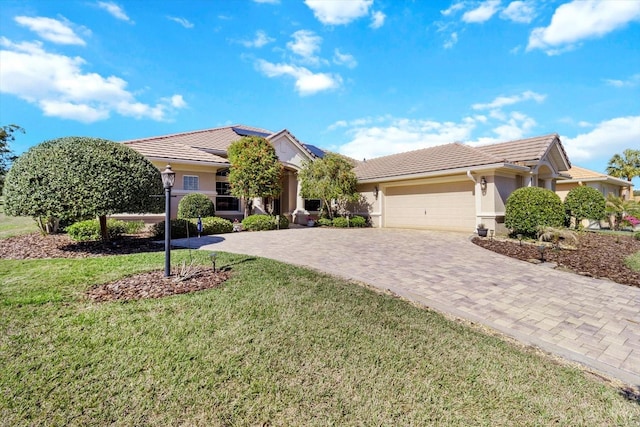 view of front facade with a front yard, solar panels, stucco siding, a garage, and a tile roof