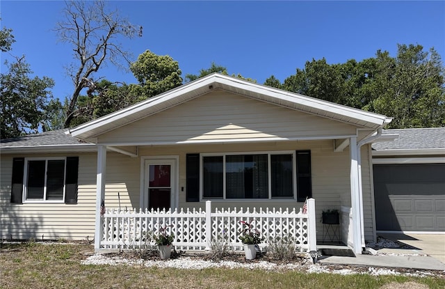 ranch-style home with a garage, roof with shingles, and a porch