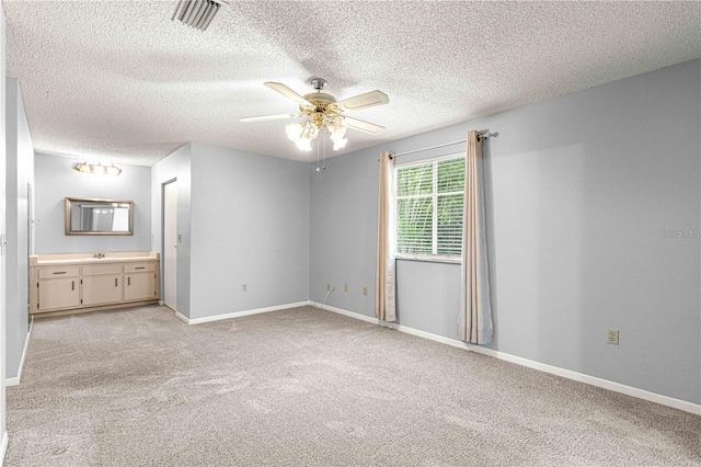 unfurnished bedroom with visible vents, a textured ceiling, and light colored carpet