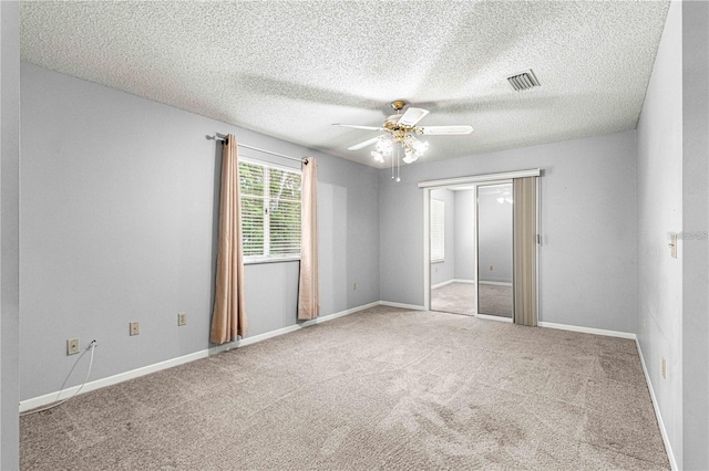 unfurnished bedroom with ceiling fan, carpet floors, a textured ceiling, and visible vents
