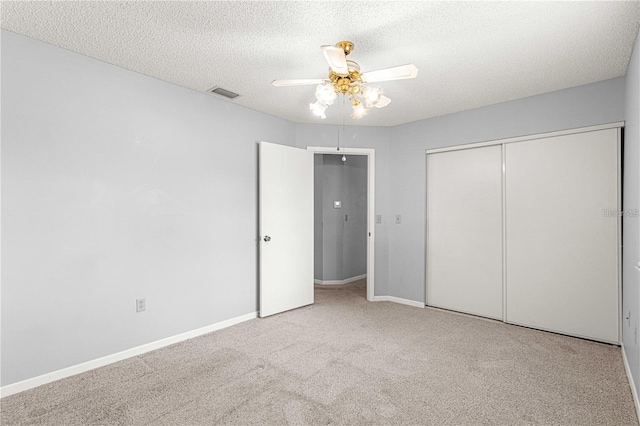 unfurnished bedroom featuring carpet flooring, a textured ceiling, visible vents, a ceiling fan, and a closet