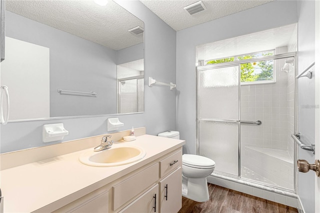 full bath with a shower stall, wood finished floors, visible vents, and toilet