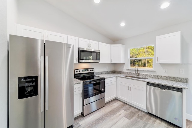 15954 SW 30th Ln, Ocala, FL 34481 - kitchen featuring vaulted ceiling, a sink, white cabinetry, light stone countertops, and stainless steel appliances