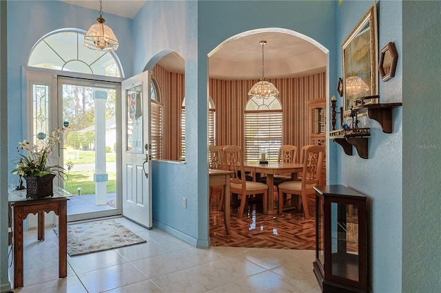 foyer entrance with arched walkways, plenty of natural light, and a chandelier