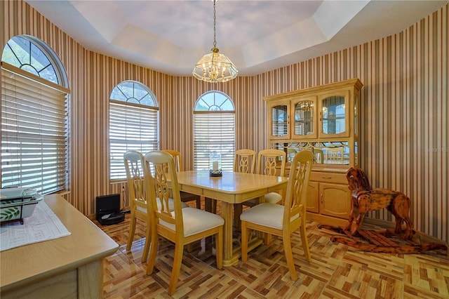 dining room with a raised ceiling, an inviting chandelier, and wallpapered walls
