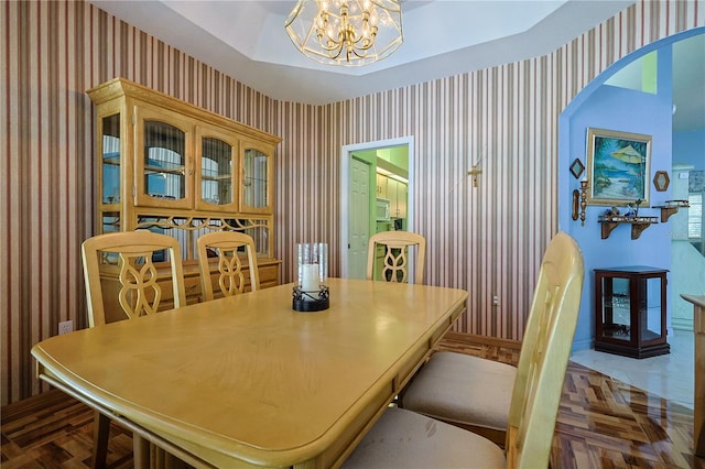 dining area featuring wallpapered walls, a notable chandelier, baseboards, and arched walkways