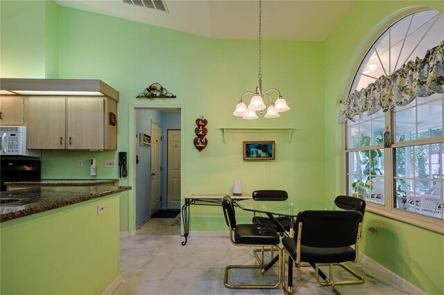 dining room with visible vents, baseboards, a notable chandelier, and a towering ceiling