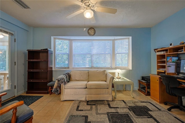 living area with light tile patterned floors, a ceiling fan, visible vents, and a wealth of natural light
