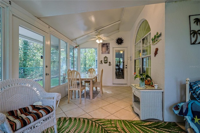 sunroom / solarium featuring ceiling fan, tile patterned floors, outdoor dining space, and vaulted ceiling