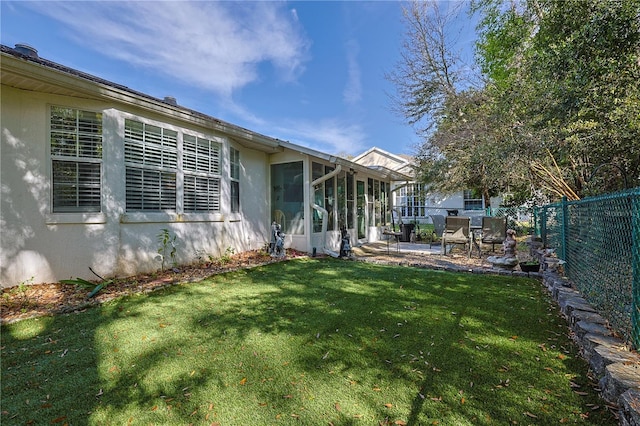 view of yard featuring a patio area, a fenced backyard, and a sunroom