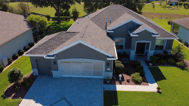 13968 SE 96th Cir, Summerfield, FL 34491 - view of front of property featuring a garage, decorative driveway, stucco siding, a front lawn, and a shingled roof