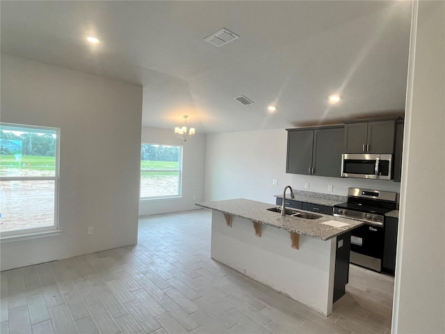 4504 SW 90th Lane Rd, Ocala, FL 34476 - kitchen featuring appliances with stainless steel finishes, light wood-style floors, a chandelier, light stone countertops, and a kitchen bar