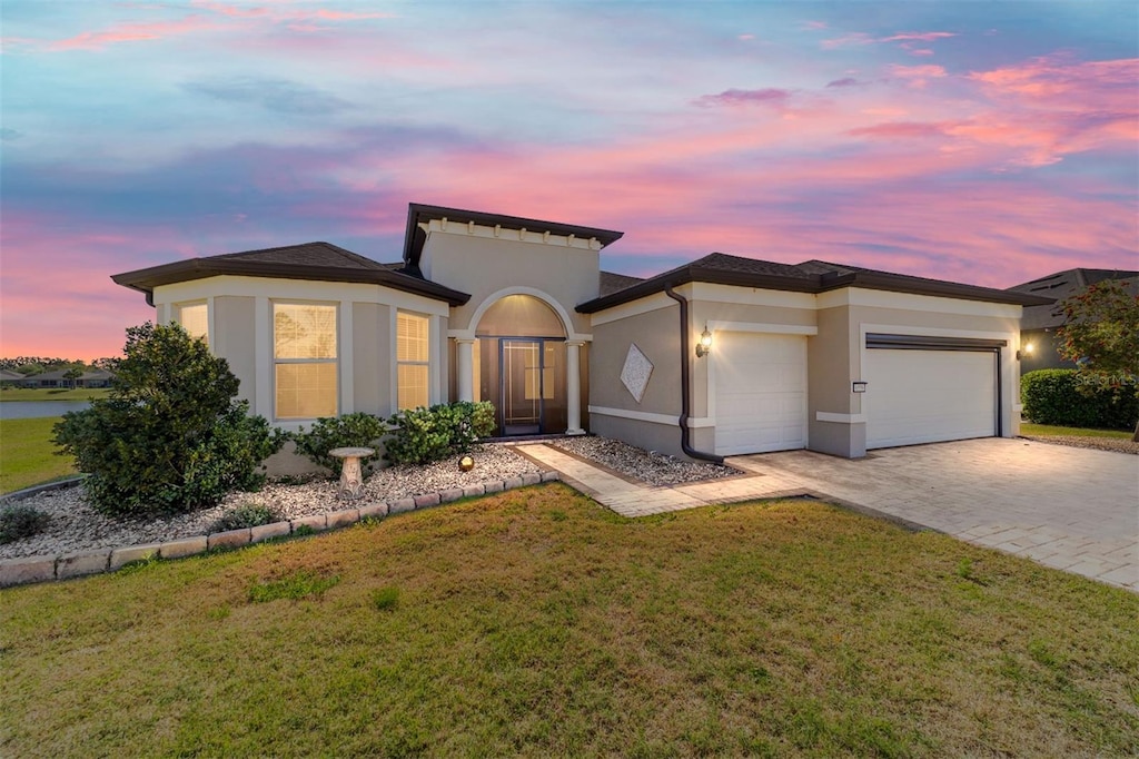 6558 SW 94th Cir, Ocala, FL 34481 - view of front facade with stucco siding, decorative driveway, a garage, and a lawn