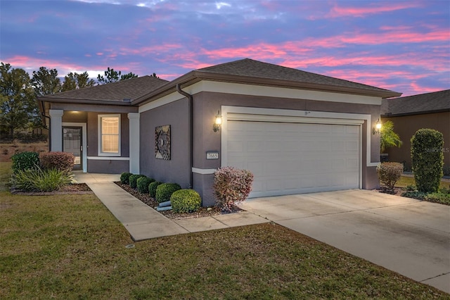 ranch-style home featuring an attached garage, a lawn, concrete driveway, roof with shingles, and stucco siding