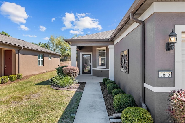 entrance to property featuring a lawn and stucco siding