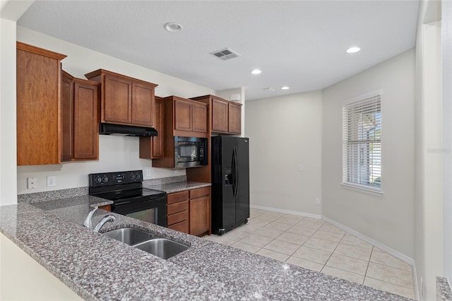 kitchen featuring a sink, under cabinet range hood, light tile patterned floors, visible vents, and black appliances
