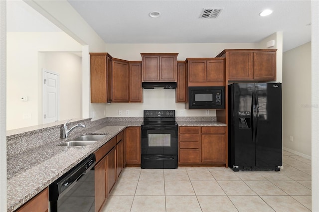 kitchen featuring visible vents, under cabinet range hood, a sink, light stone counters, and black appliances