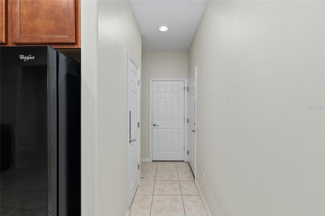 hall featuring light tile patterned flooring and baseboards