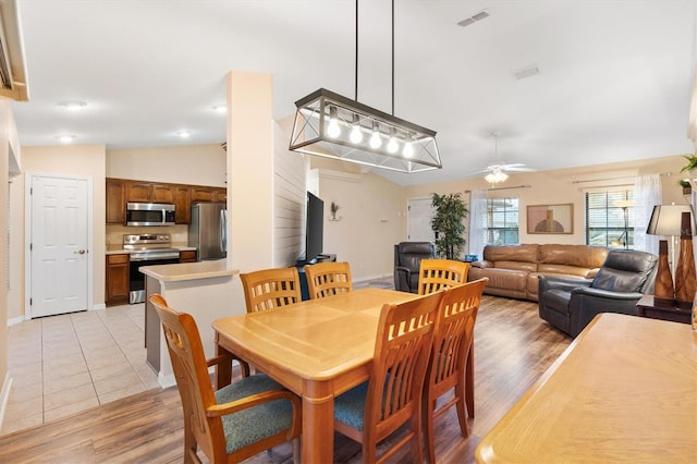 dining space featuring visible vents, lofted ceiling, light wood-style floors, and ceiling fan