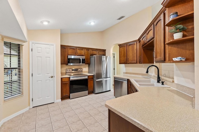 kitchen featuring open shelves, a sink, appliances with stainless steel finishes, light countertops, and lofted ceiling
