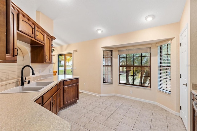 kitchen with light tile patterned floors, a healthy amount of sunlight, light countertops, and a sink