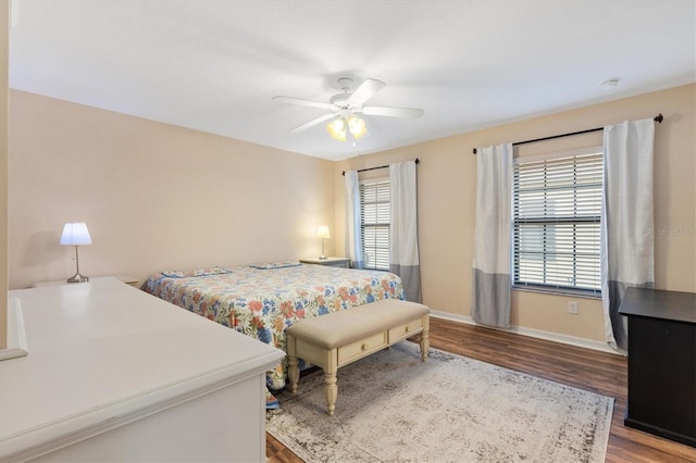 bedroom featuring ceiling fan, baseboards, multiple windows, and wood finished floors