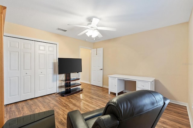 living room featuring visible vents, wood finished floors, baseboards, and ceiling fan