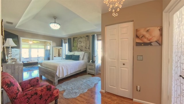 5291 NW 20th Pl, Ocala, FL 34482 - bedroom featuring visible vents, baseboards, an inviting chandelier, wood finished floors, and a raised ceiling