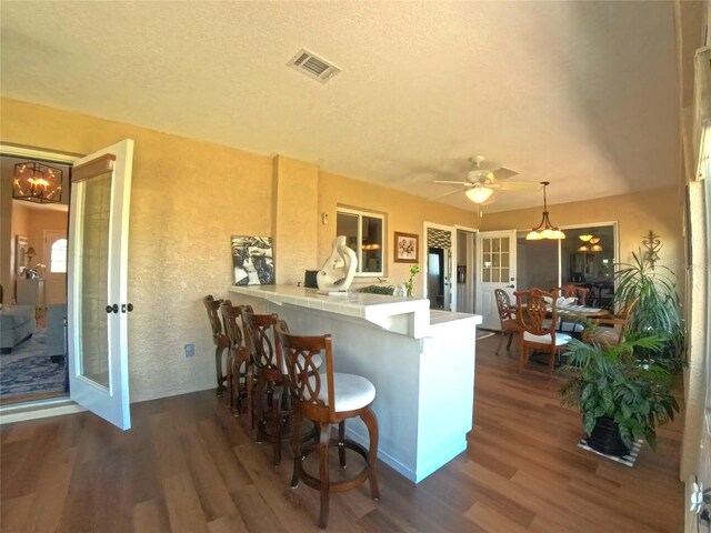 5291 NW 20th Pl, Ocala, FL 34482 - kitchen with visible vents, a peninsula, dark wood-style flooring, a kitchen breakfast bar, and ceiling fan with notable chandelier