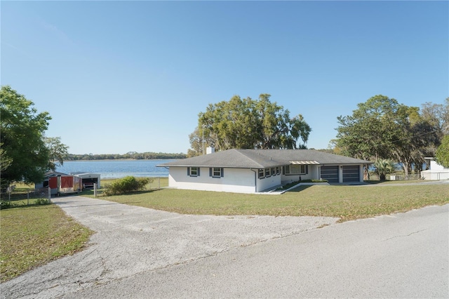390 SW Shorewood Dr, Dunnellon, FL 34431 - ranch-style home with driveway, a water view, a front lawn, and an outbuilding
