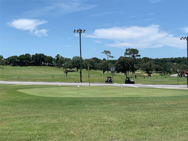 view of community with view of golf course and a yard