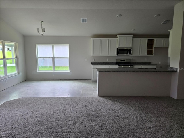 310 W Rexford Dr, Beverly Hills, FL 34465 - kitchen featuring appliances with stainless steel finishes, light tile patterned floors, white cabinetry, and light colored carpet