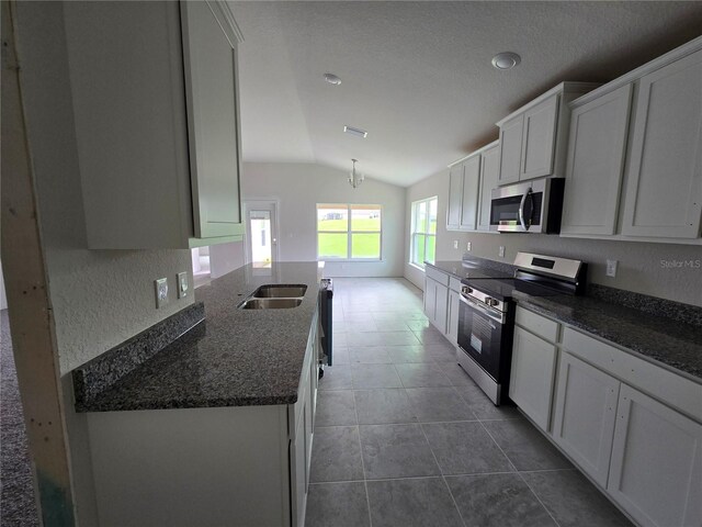 310 W Rexford Dr, Beverly Hills, FL 34465 - kitchen with appliances with stainless steel finishes, lofted ceiling, white cabinetry, dark stone counters, and dark tile patterned flooring