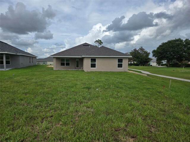 310 W Rexford Dr, Beverly Hills, FL 34465 - rear view of property with stucco siding, a lawn, and a shingled roof