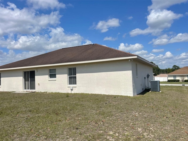 rear view of property with central air condition unit, a yard, and stucco siding