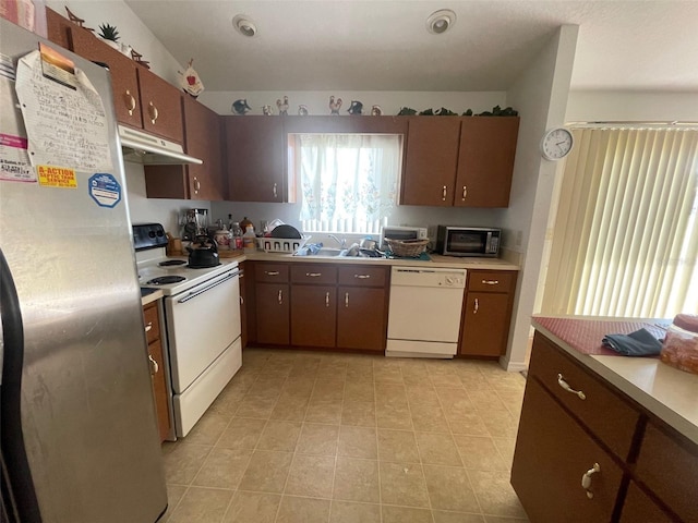 kitchen featuring under cabinet range hood, appliances with stainless steel finishes, light countertops, and a sink