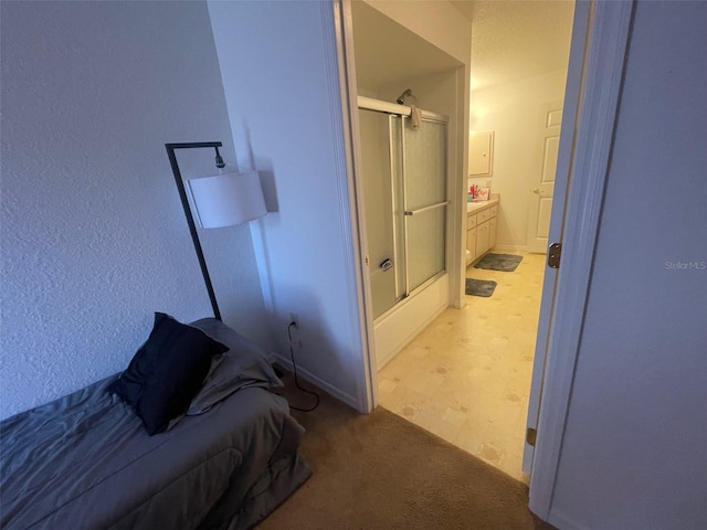 bedroom with ensuite bath and light colored carpet