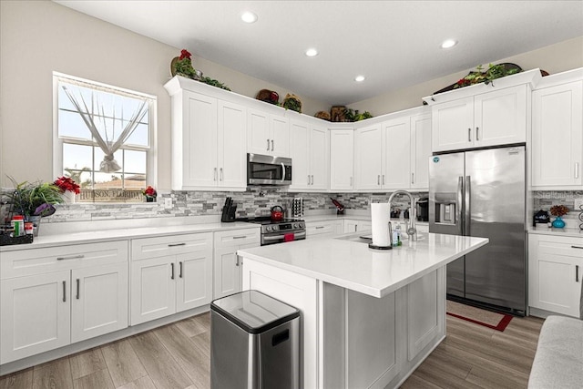 kitchen featuring decorative backsplash, appliances with stainless steel finishes, a sink, light countertops, and white cabinetry