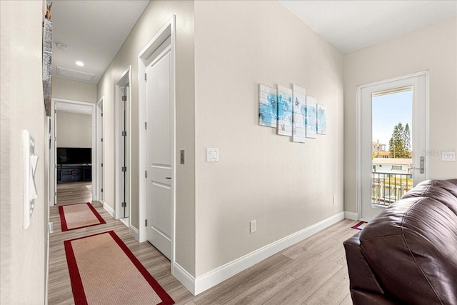 corridor with light wood-style floors and baseboards