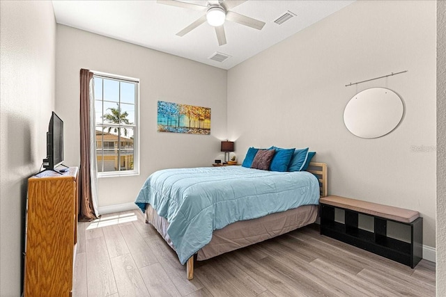bedroom with baseboards, ceiling fan, wood finished floors, and visible vents