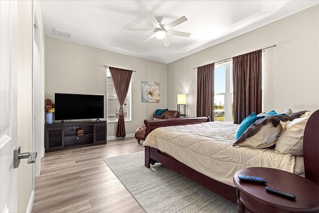 bedroom featuring visible vents, light wood-style flooring, ceiling fan, and baseboards