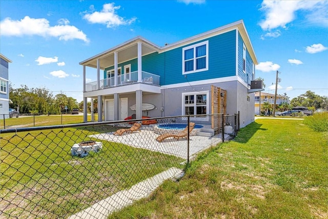 back of house with fence, stucco siding, a yard, and a balcony
