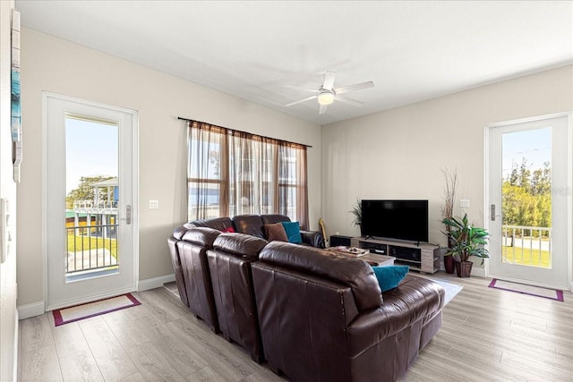 living room with light wood-type flooring, ceiling fan, and a wealth of natural light